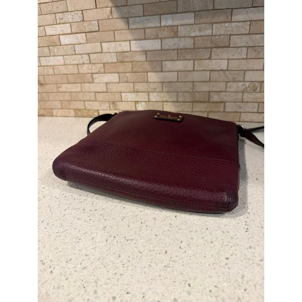 Kate Spade New York pebbled leather crossbody bag in a deep burgundy/wine color.